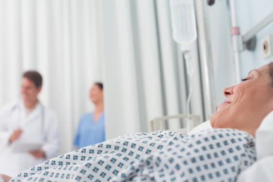 Patient lying on a medical bed next to a doctor and a nurse in hospital ward